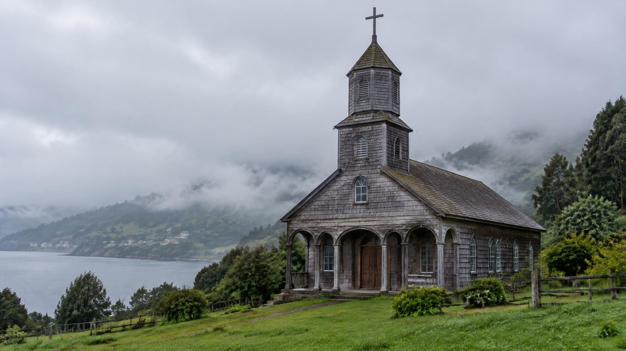 Wooden church of Chiloe surrounded by green hills and mist