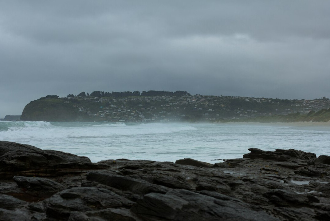 Old lighthouse on a rocky southern coast under a stormy sky